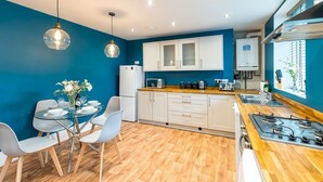 Una cocina compacta con armarios blancos, encimera de madera y cocina a gas.