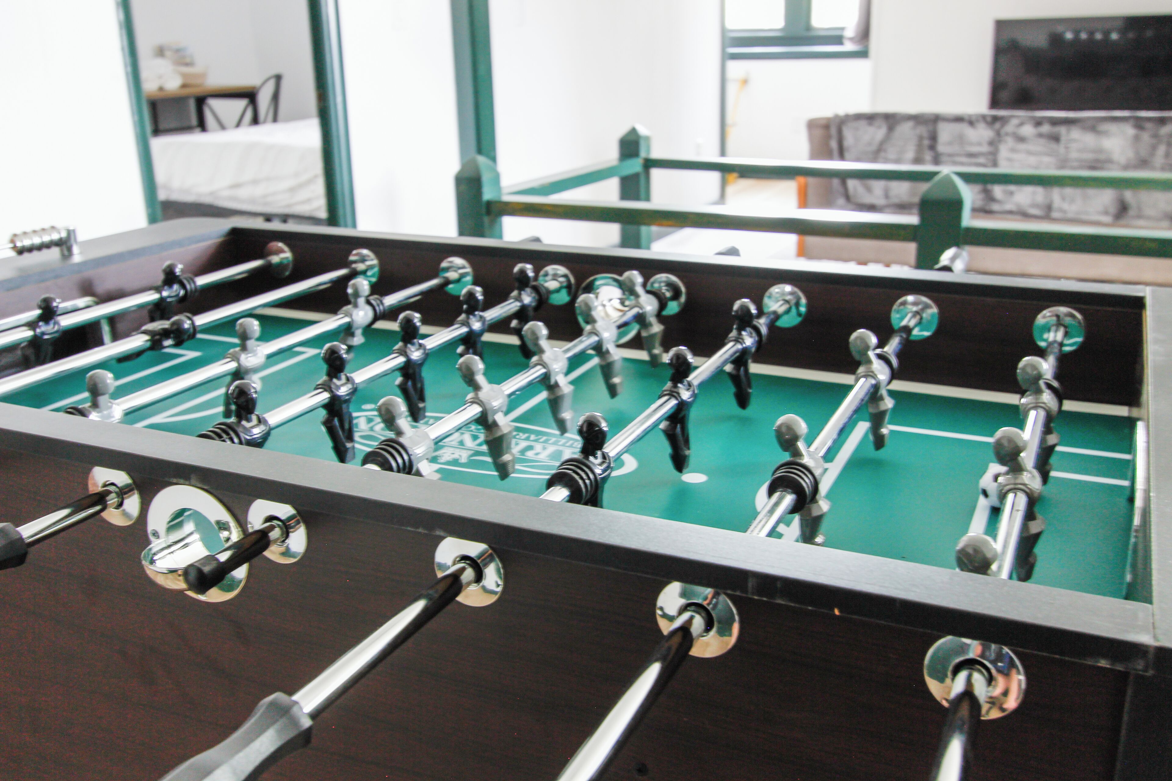 A foosball table with a green playing surface and metal rods.