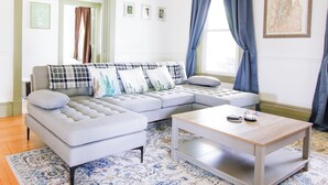 Una sala de estar con un sofá seccional gris, una mesa de centro de madera y una alfombra estampada.