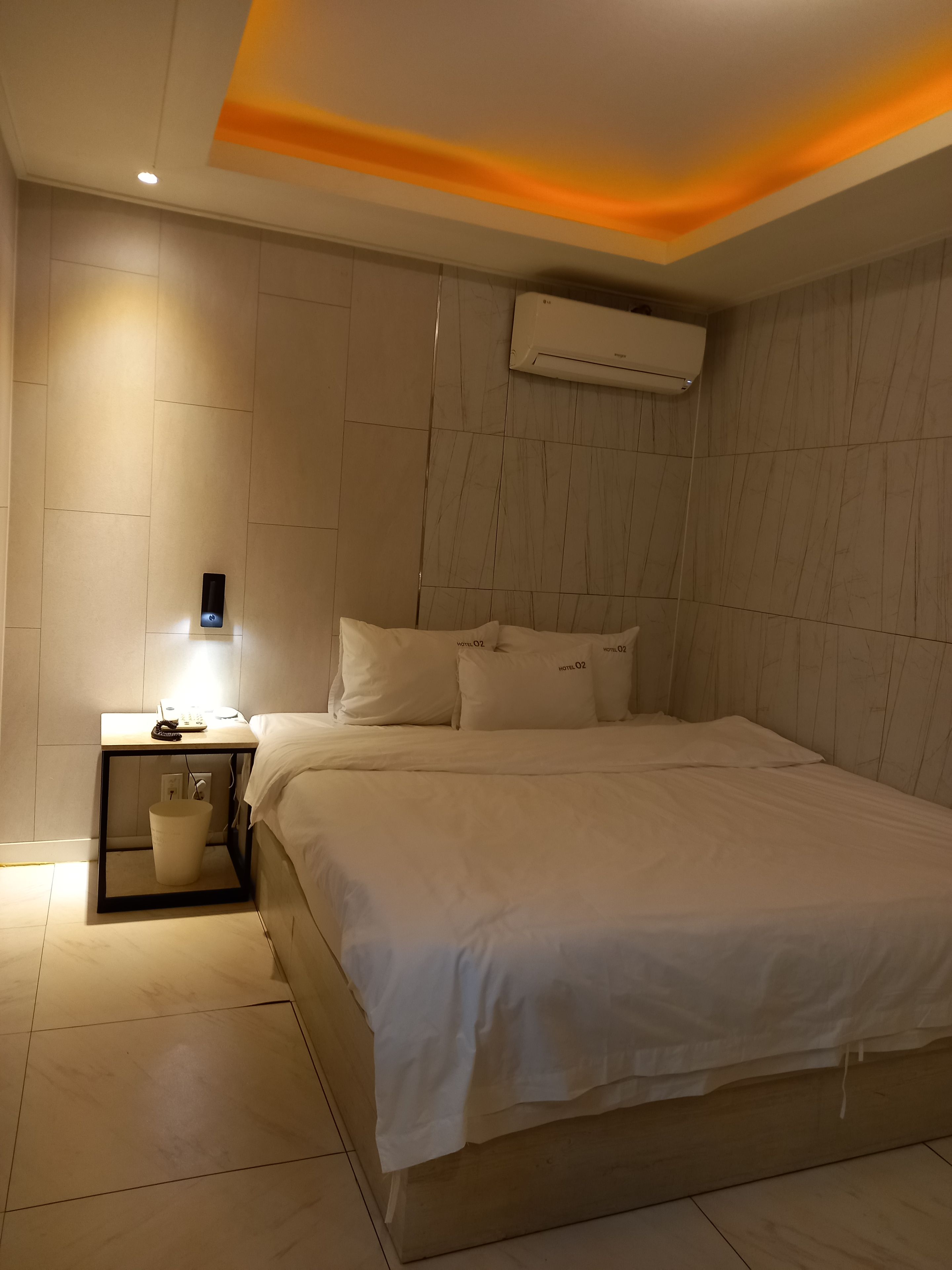 Une chambre d’hôtel équipée d’un lit, d’une table de chevet et d’un climatiseur fixé au mur.