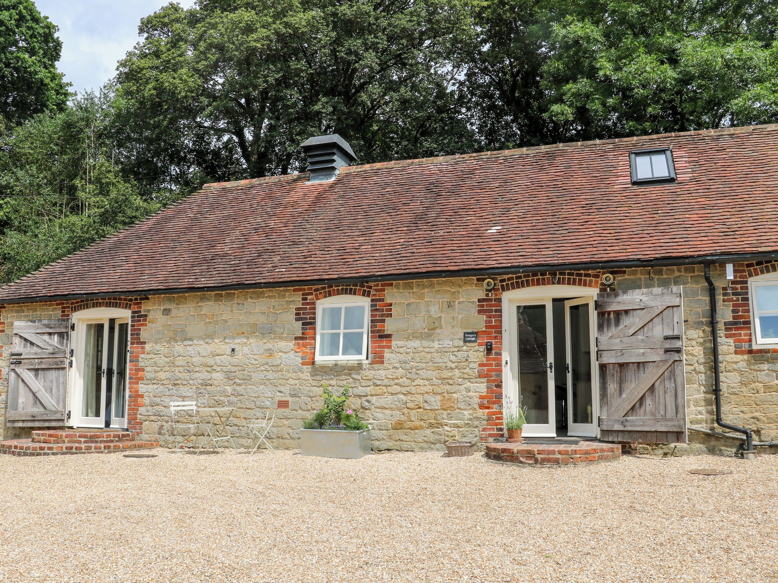 A stone building with a tiled roof, two wooden doors, and a small window.