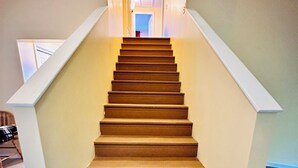 A staircase with a handrail, carpeted steps, and a light-colored wall. - Beautiful and private lakefront home on the sandy shores of South Twin Lake (Indian Purchase Township)