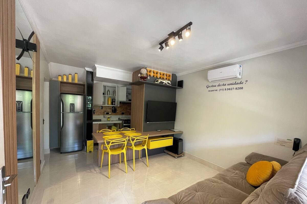 A modern kitchen with a dining area, a TV, and a sofa in a living room.