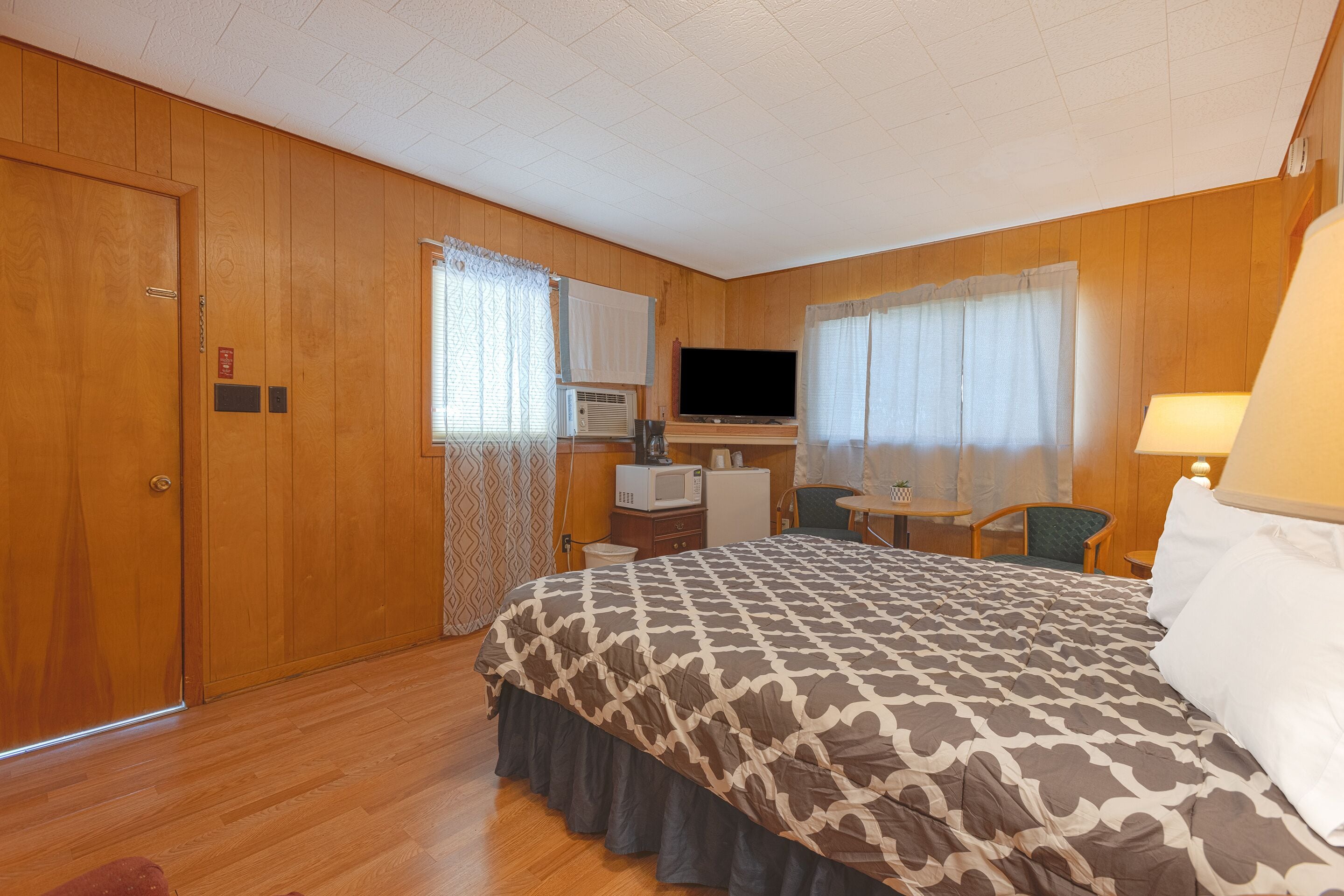 Une chambre d’hôtel avec un grand lit, un bureau avec une télévision, un four à micro-ondes et une petite table avec une chaise.