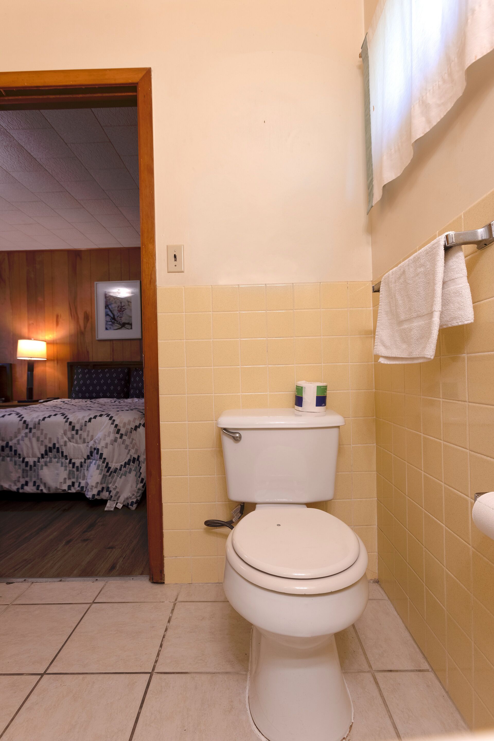 A bathroom with a toilet, tiled walls, and a towel rack.
