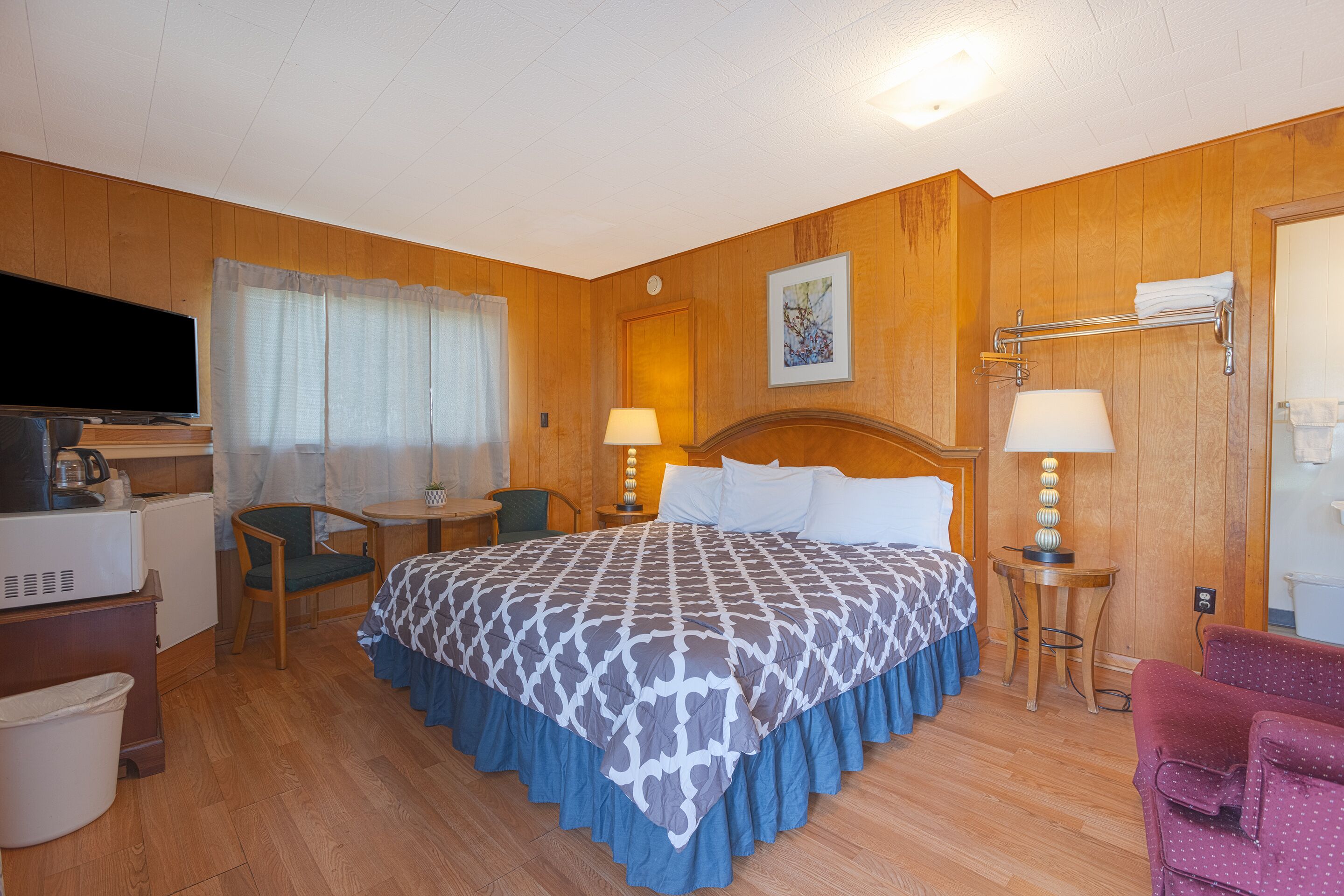 Ein Hotelzimmer mit Bett, Schreibtisch, Stuhl, Fernseher und Badezimmer.