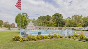 Zona de piscina con una bandera, sillas de descanso y un cerramiento.