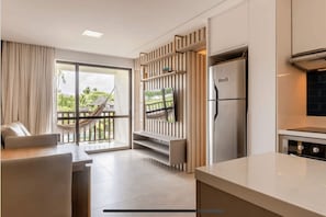 Enjoy a serene retreat with a balcony overlooking lush greenery, a sofa, and a dining table in a clean and inviting space.