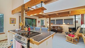 Una cocina moderna con una isla central, vigas de madera y un área de comedor con sofá y sillas.