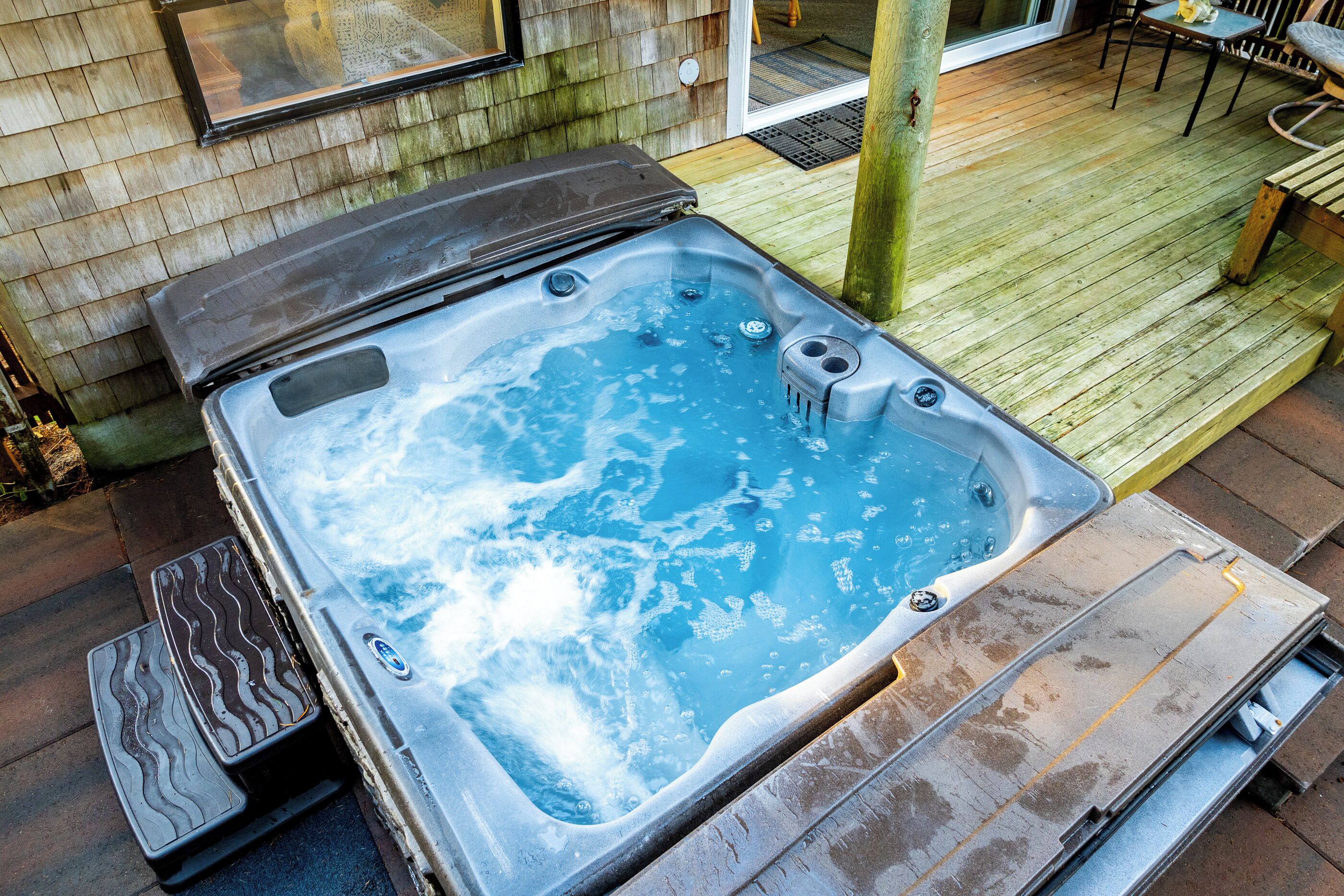 A hot tub on a wooden deck with steps leading up to it.