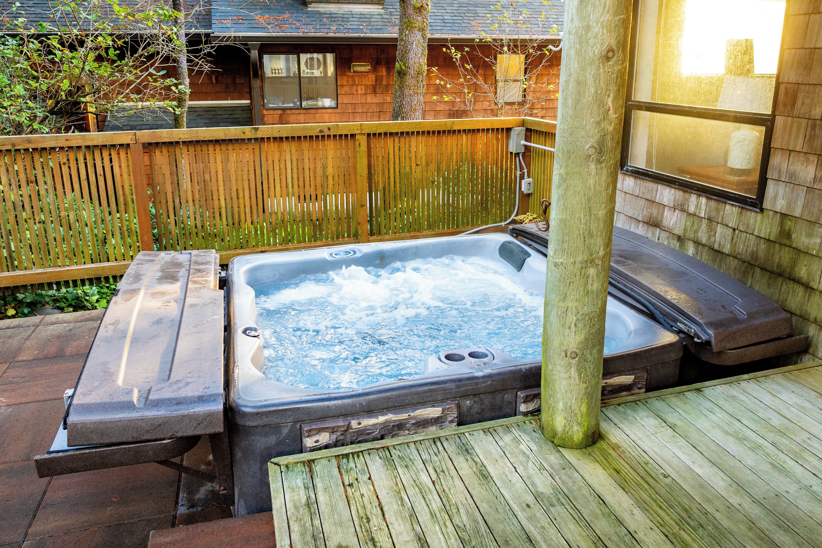 Un bain à remous avec une terrasse en bois et une clôture en bois en arrière-plan.