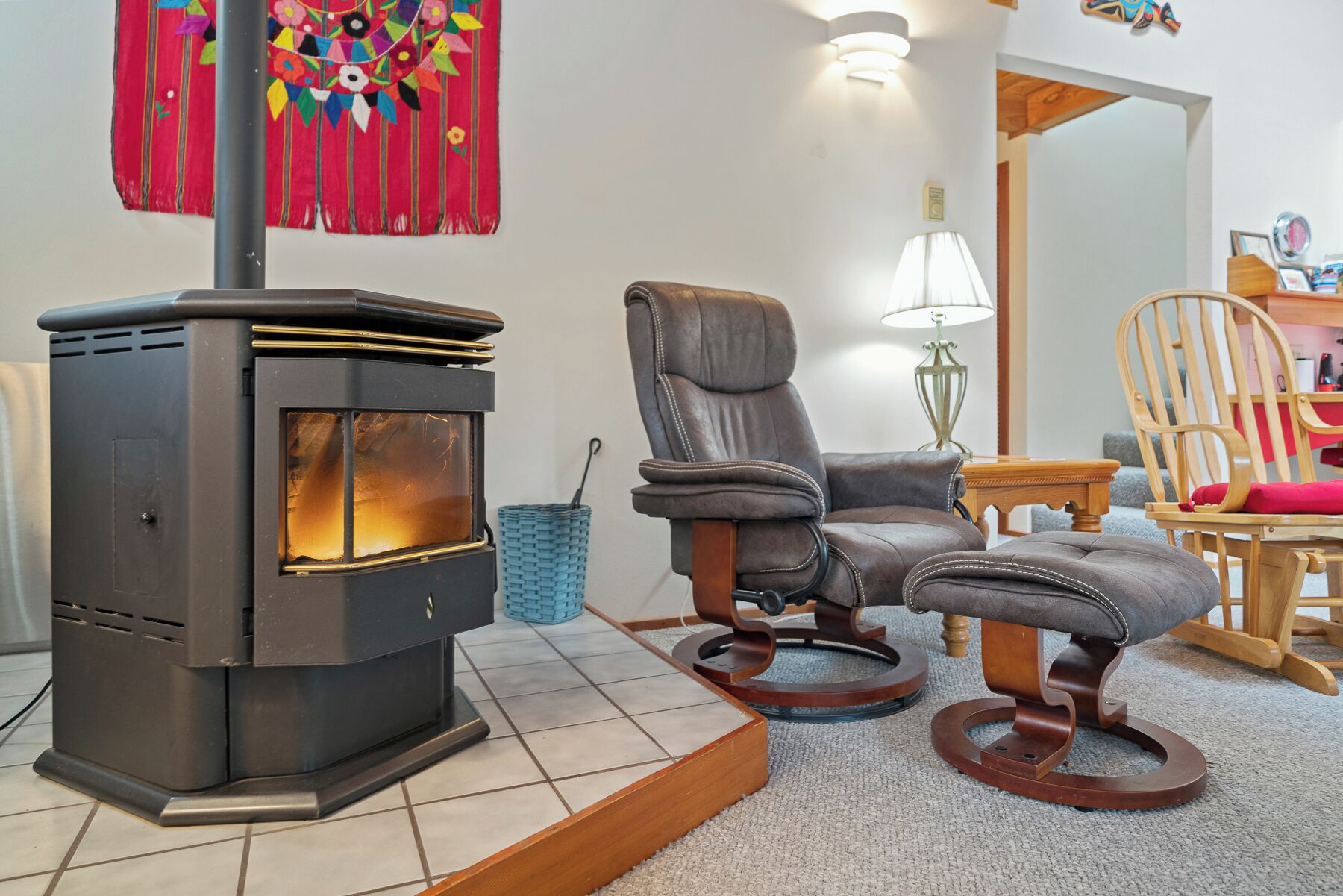 Une pièce chaleureuse avec un poêle à bois, deux fauteuils en cuir, une petite table et une lampe.