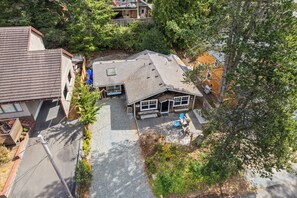 A residential property with a detached house featuring a sloped roof, a front porch with a bench, and a small garden area. - Blue Heaven is close to town and beach, fireplace, dogs ok, EV charger (Manzanita)