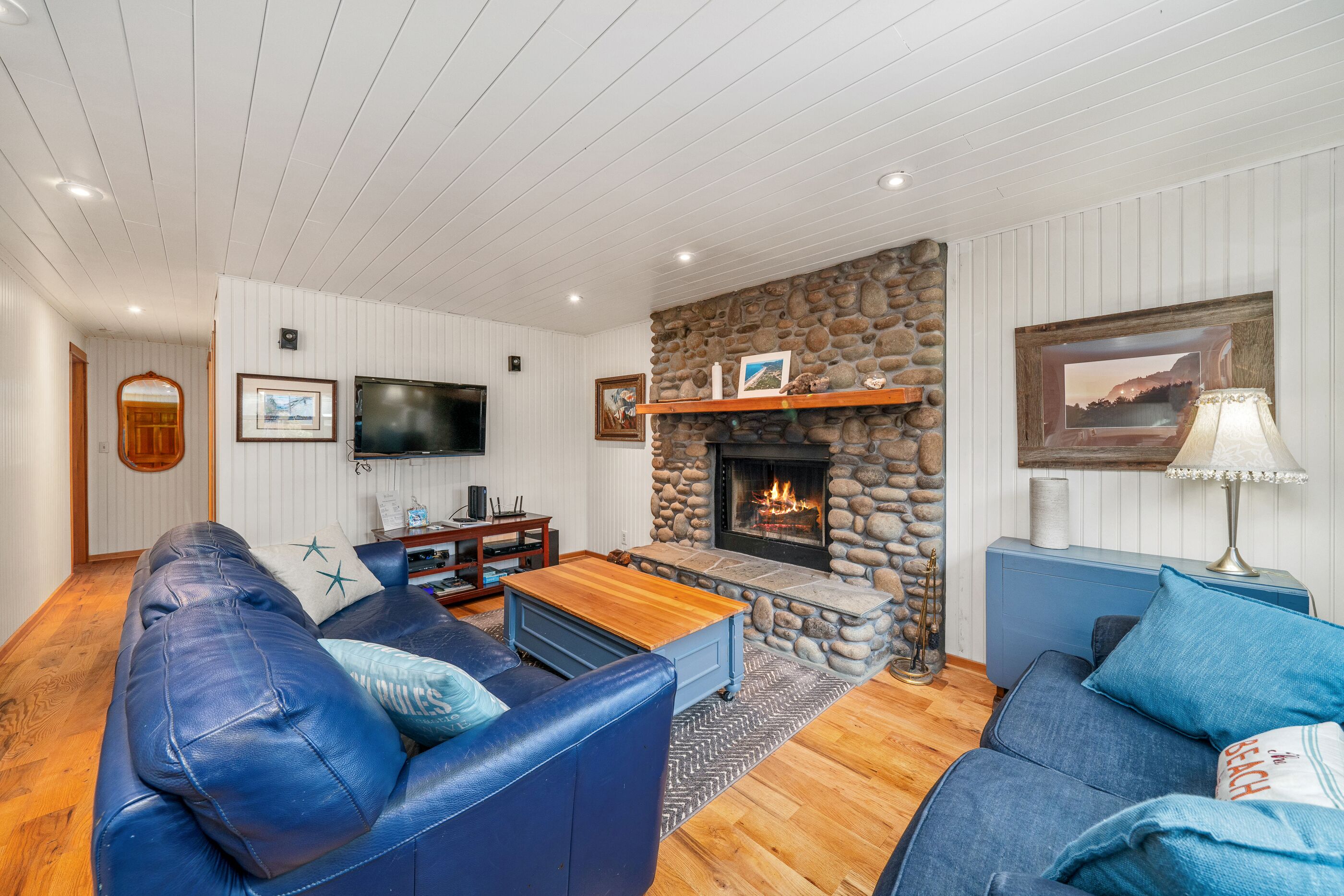 Una sala de estar acogedora con chimenea de piedra, sofás azules y televisor.