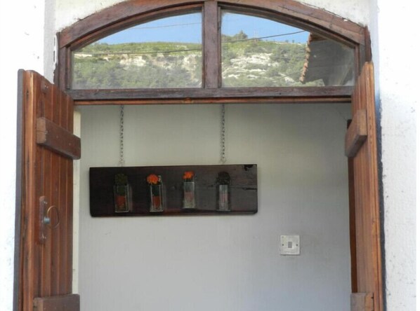 Una puerta de madera rústica con un ventanal superior que muestra un paisaje montañoso.