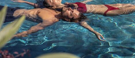 Two people floating in a clear pool.