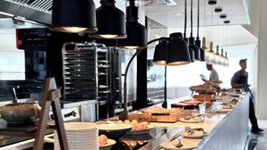Montaje de bufé con diferentes alimentos y un chef de fondo.
