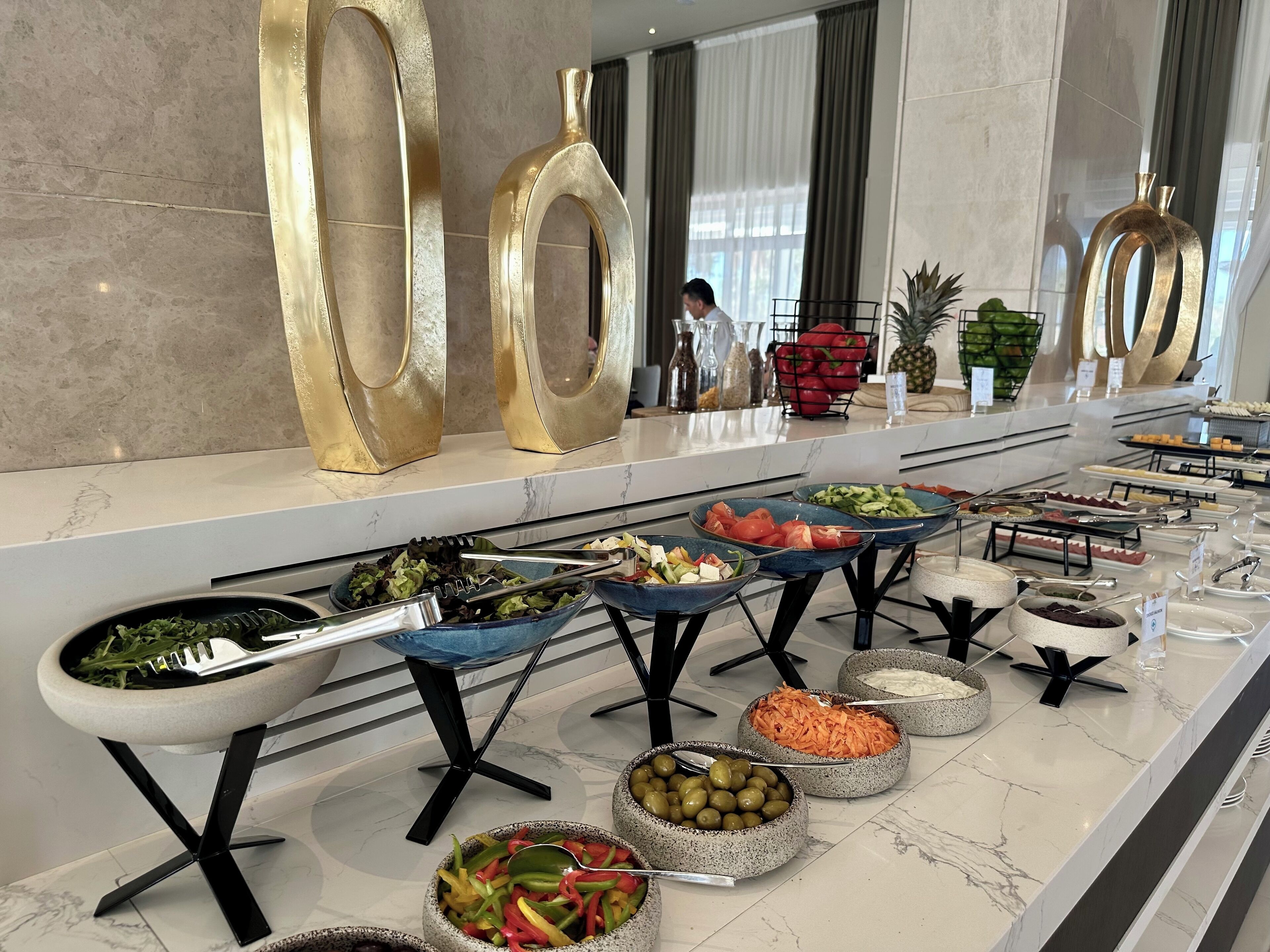 Un buffet con diversi cibi e una persona sullo sfondo.