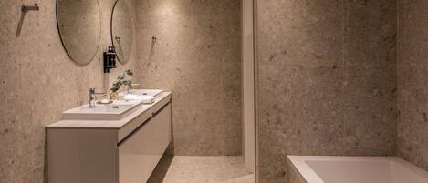 A modern bathroom with a large bathtub, a double sink vanity, and two wall-mounted mirrors.