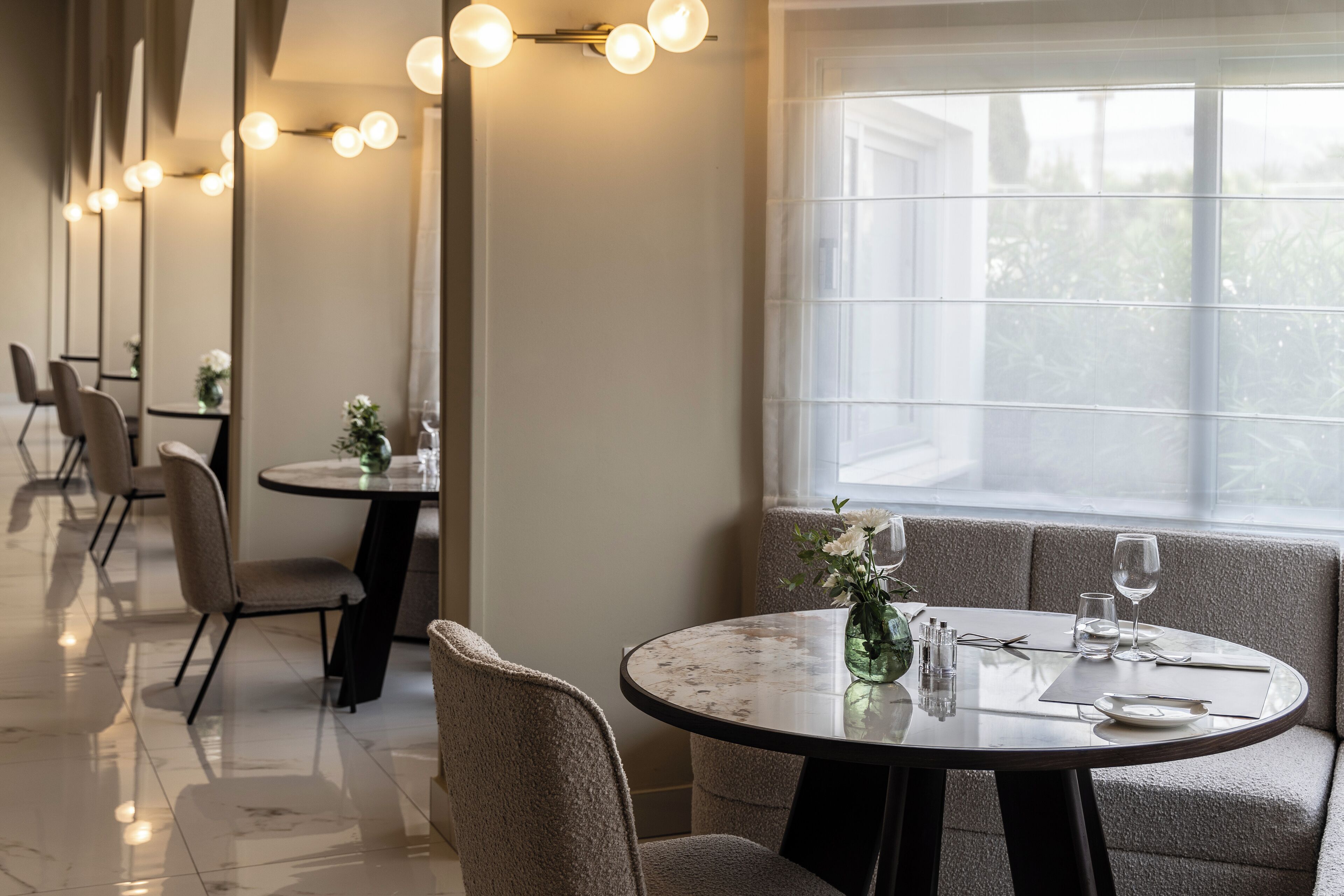 A dining area with round tables, chairs, and a large window.