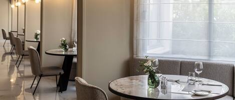 A dining area with round tables, chairs, and a large window.