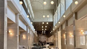 Un hallo espacioso con muebles modernos, un techo alto con lámparas colgantes y vistas del interior a través de amplias ventanas.