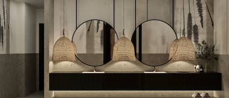 A modern bathroom with a large mirror, three sinks, and a dark vanity.
