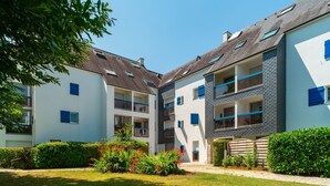 A modern apartment building with multiple balconies, a well-maintained garden, and a clear blue sky. - Les Cormorans - Appt en rdc avec jardin (Benodet)