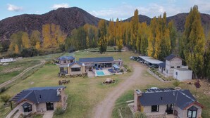 A residential area with multiple houses, a swimming pool, and a mountainous backdrop.