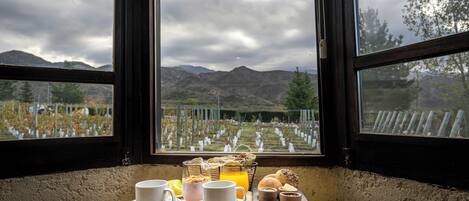 Una mesa con alimentos para el desayuno y vista a un cementerio a través de una ventana.