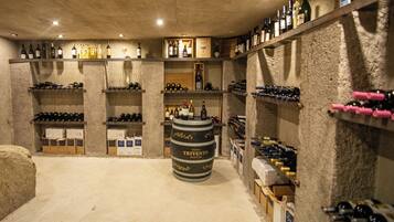 Una cava de vinos con estantes llenos de botellas y un barril grande con la etiqueta 'TRIVENTO'.