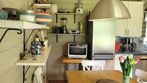 Une cuisine de taille réduite avec une table en bois, un grille-pain, un mixeur et un réfrigérateur.