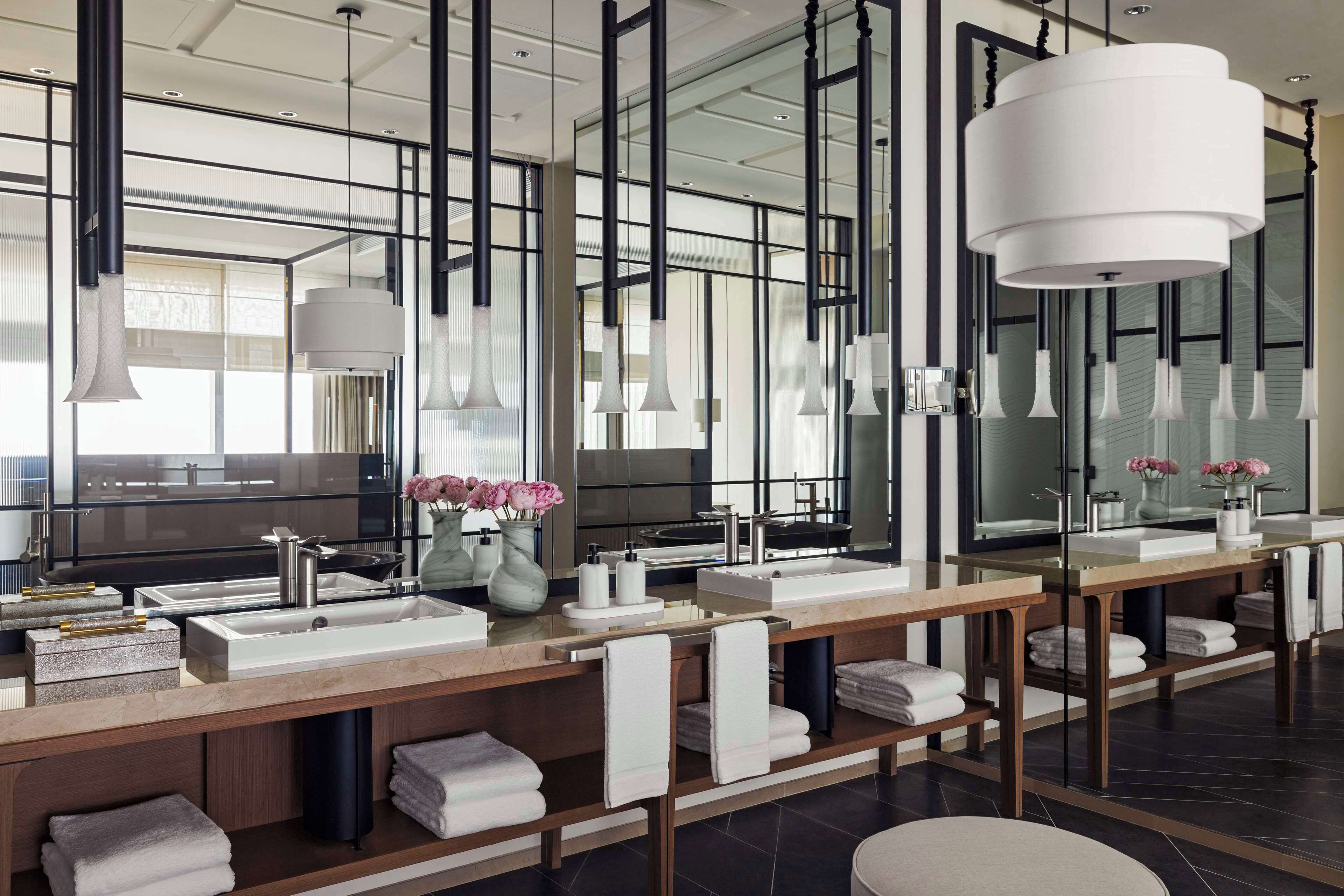 A modern bathroom with dual sinks, large mirrors, and hanging pendant lights.