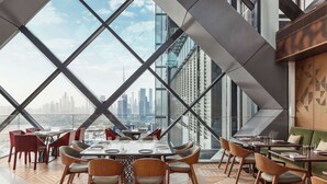 Un espace repas moderne offrant une vue panoramique sur la ville, avec des cloisons en verre aux motifs géométriques et un plancher en bois.