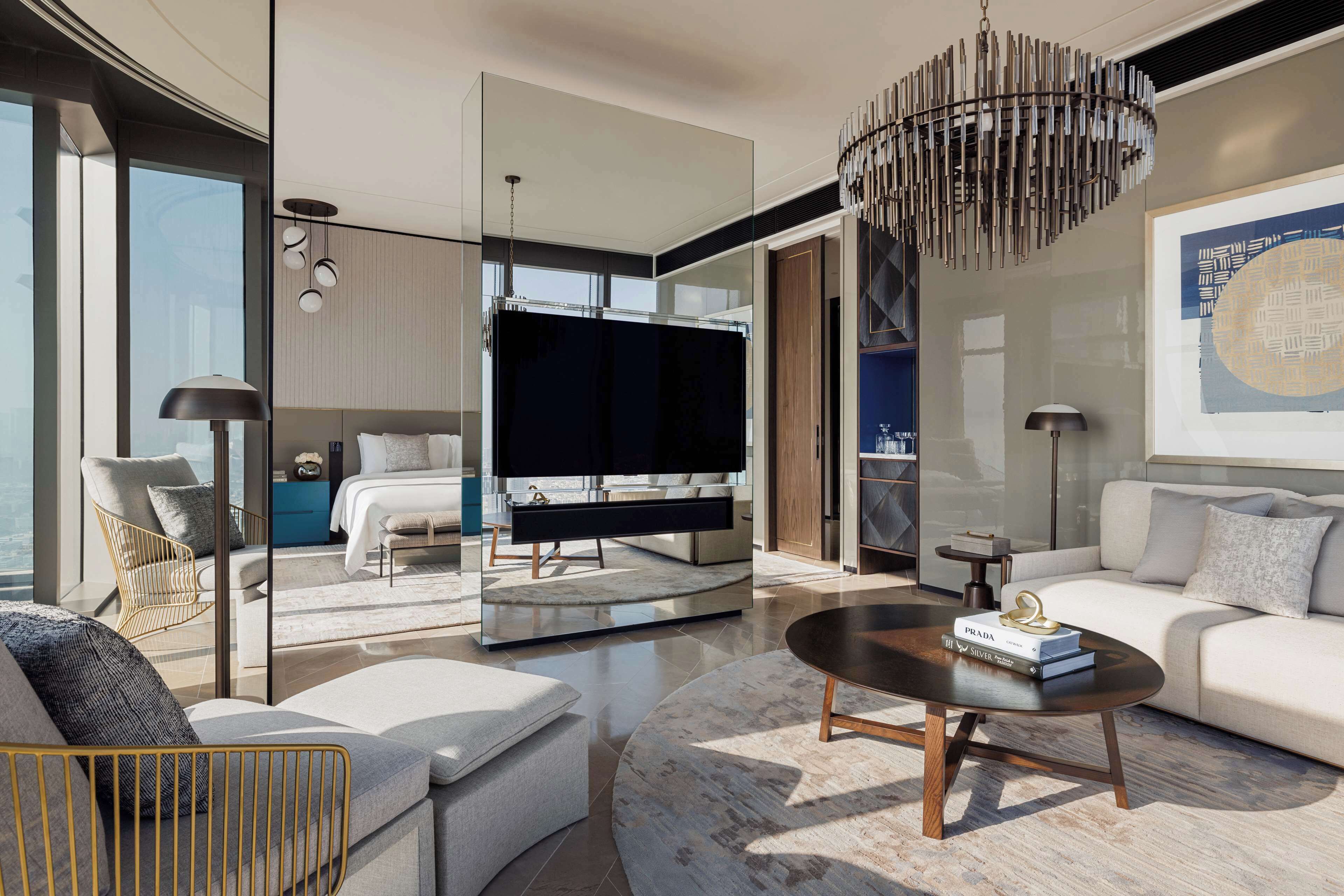 A modern living room with a large flat-screen TV, a round coffee table, and a sofa.