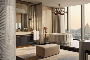 A modern bathroom with a large window, a round bathtub, and a vanity with a mirror and towel rack.