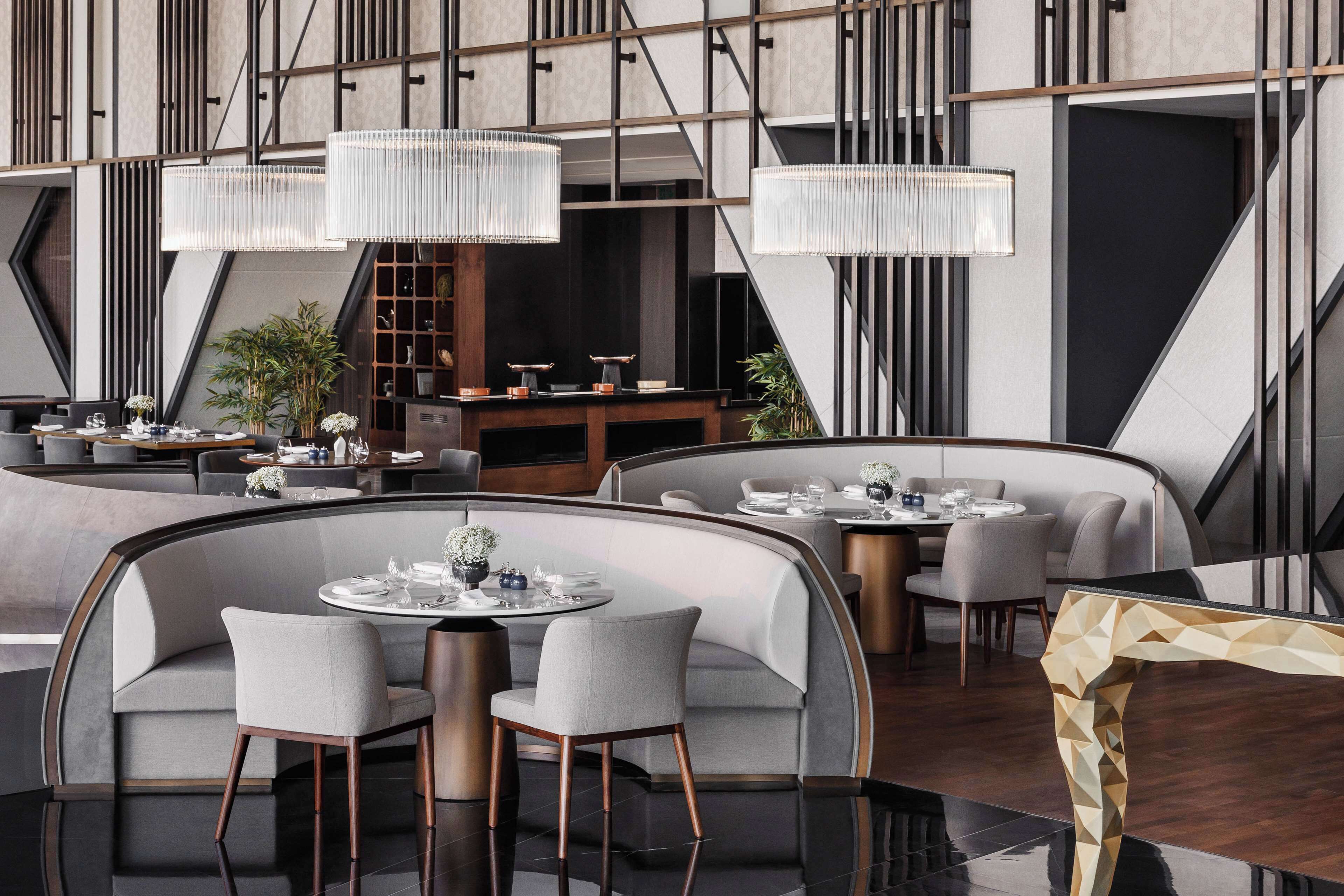 Un restaurante moderno con asientos curvos, iluminación colgante y un diseño de pared geométrico.