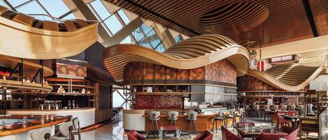 A modern restaurant with a high ceiling, exposed beams, and a central bar area.