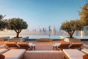 En takterrass med bekväma fåtöljer, en pool och utsikt över stadens skyline.