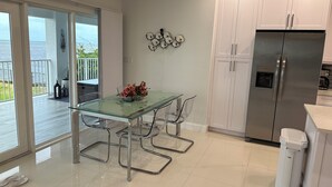 A modern kitchen with a glass dining table, stainless steel appliances, and a view to the outside. - Breathtaking sunrises from your balcony at this 3 bedroom, 2 bath home (Big Pine Key)