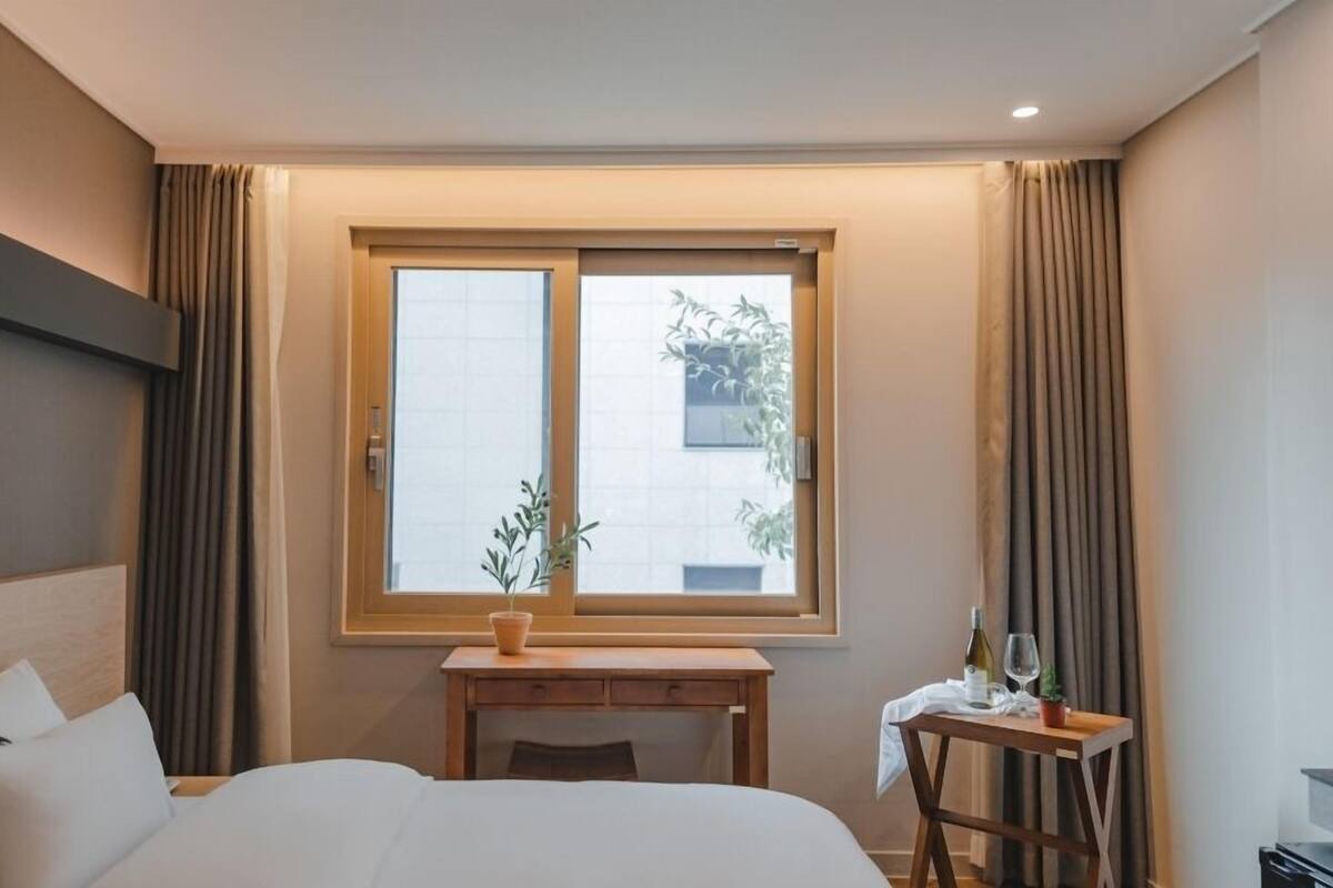 Ein Hotelzimmer mit Bett, Schreibtisch und einem fenster mit Vorhängen.
