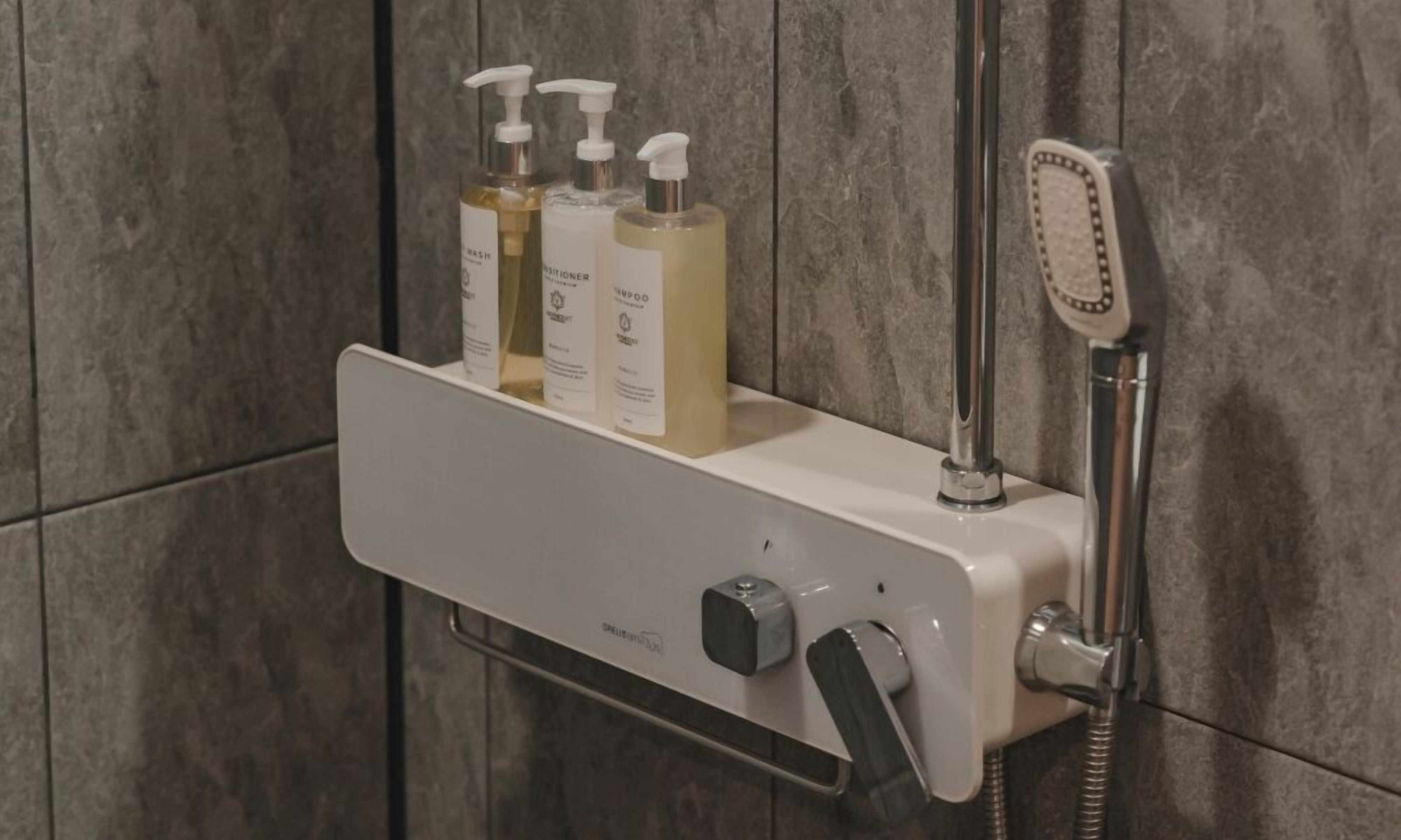 Un espacio de ducha con cabezal de ducha de mano, dispensador de jabón y dos botellas de champú.
