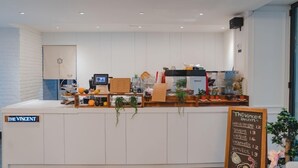 A clean, modern cafe interior with a menu board, a cash register, and various plants. - Jeonju Hotel The Vincent (Jeonju)