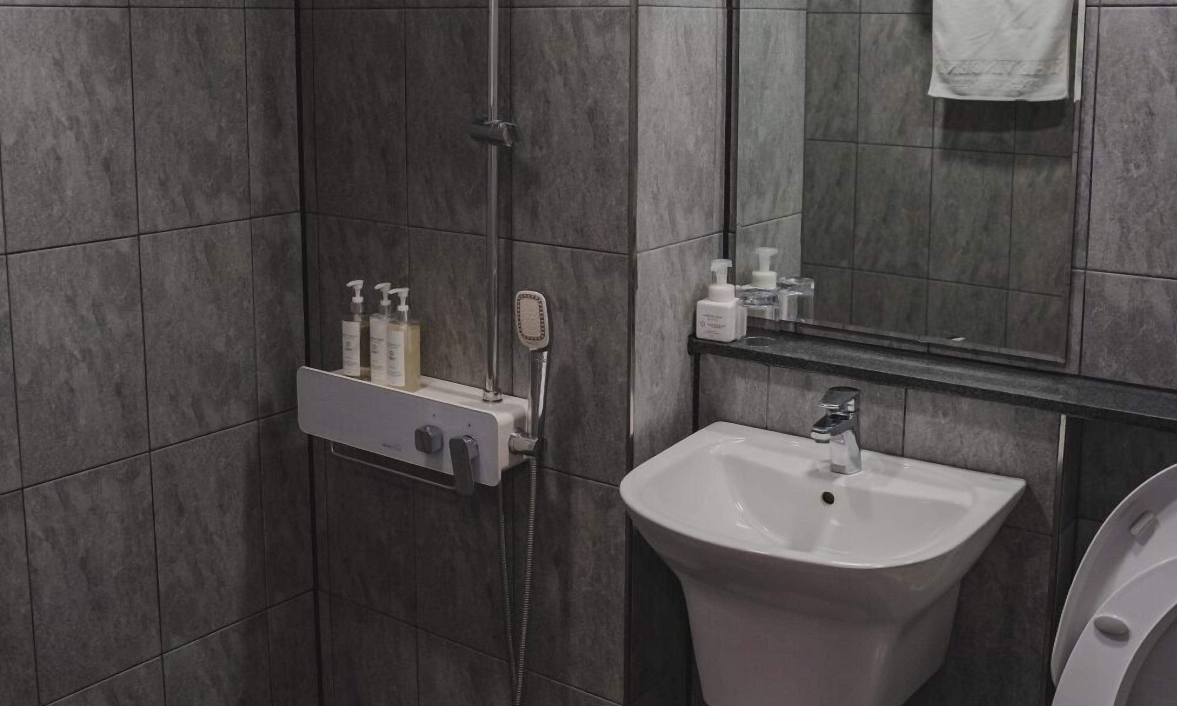 A modern bathroom with a shower, sink, and toilet.