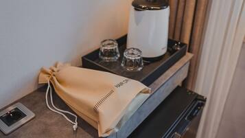 Habitación de hotel con minibar, secador de pelo y bolsa para toallas sobre la encimera.