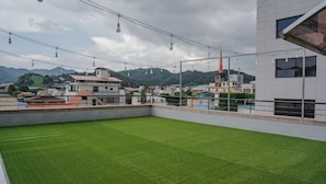 A rooftop with artificial grass, a view of buildings, and a cloudy sky. - Jeonju Hotel The Vincent (Jeonju)