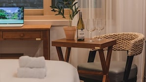 A hotel room with a bed, a wooden desk with a laptop, a potted plant, a bottle of wine, and two glasses. - Jeonju Hotel The Vincent (Jeonju)