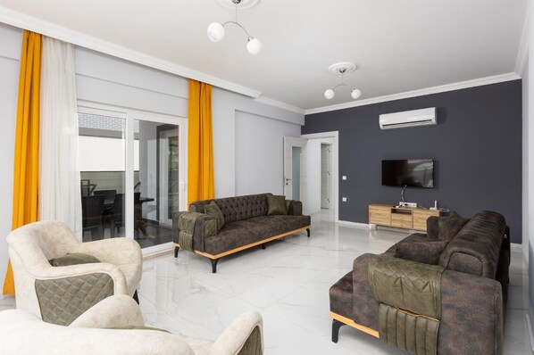 Una sala moderna con un conjunto de sofá, un televisor y un mueble de madera.