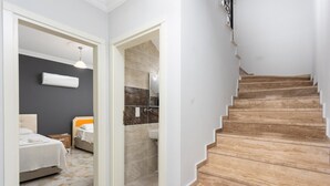 Una escalera lleva a un baño con ducha y una cama con mesita de noche.