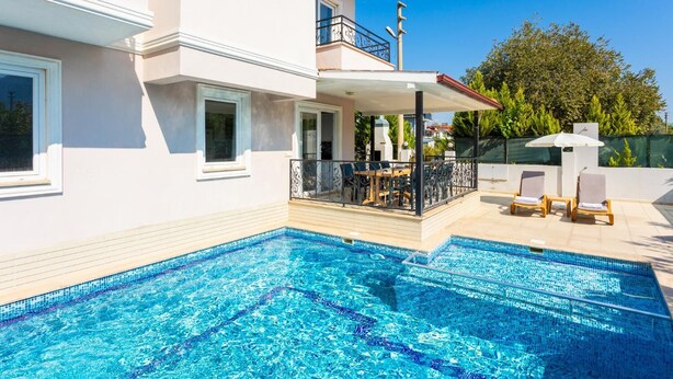 Una casa moderna de dos pisos con piscina, mobiliario exterior y un patio cubierto.